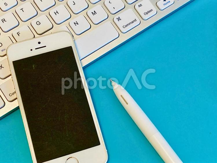 スマホとキーボードと白いペン（青背景） 仕事,ビジネス,パソコンの写真素材
