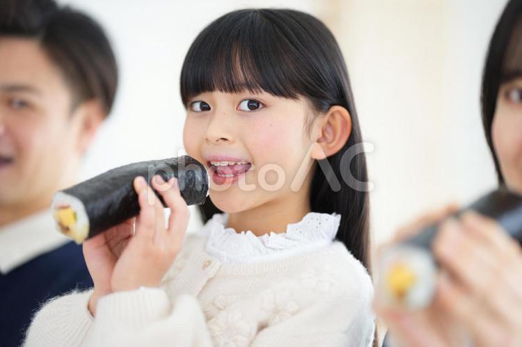 カメラ目線で恵方巻を食べる女の子 女の子,男性,女性の写真素材
