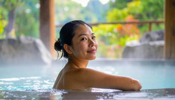 温泉につかってリラックスする若い女性 温泉につかってリラックスする若い女性の写真