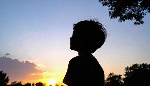 夕焼けの空を見つめる日本人の少年 夕焼けの空を見つめる日本人の少年の写真