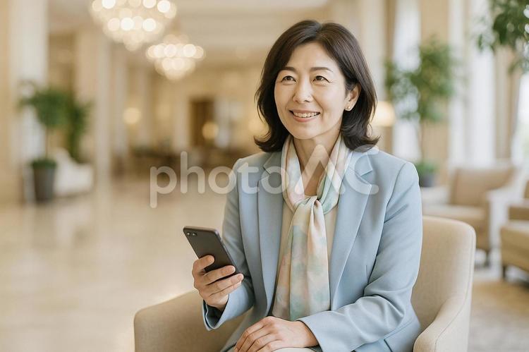スマホ片手にホテルで待ち合わせをする女性 女性,リフレッシュ,中高年の写真素材