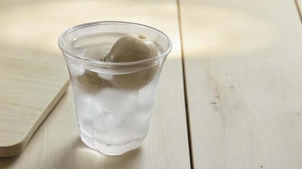 ナチュラルな木製の机に置いた梅酒のグラス ナチュラルな木製の机に置いた梅酒のグラス 自家製,梅入り,晩酌の写真素材