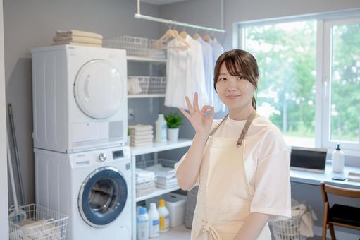 洗濯場でOKを出す可愛い女性 ランドリー,洗濯機,乾燥機の写真素材