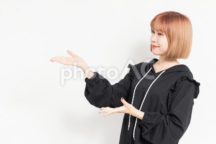 案内のジェスチャーをする若い女性 案内,こちら,若いの写真素材