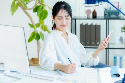 オフィスでスマホを持つビジネスウーマン スマホ,笑顔,ビジネスウーマンの写真素材