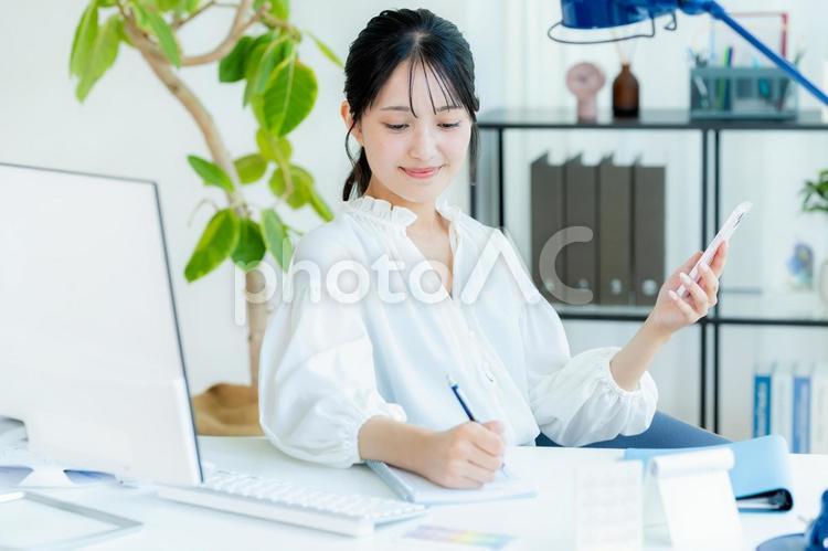 オフィスでスマホを持つビジネスウーマン スマホ,笑顔,ビジネスウーマンの写真素材