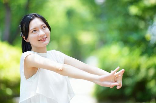 白いノースリーブワンピースの女性が両手を前に差し出す 女性,腕を伸ばす,ストレッチの写真素材