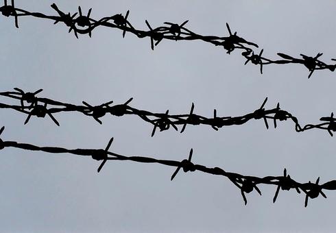 監獄イメージ 有刺鉄線と曇り空の境界線 監獄イメージ 有刺鉄線と曇り空の境界線 収容所,監獄,拘束の写真素材