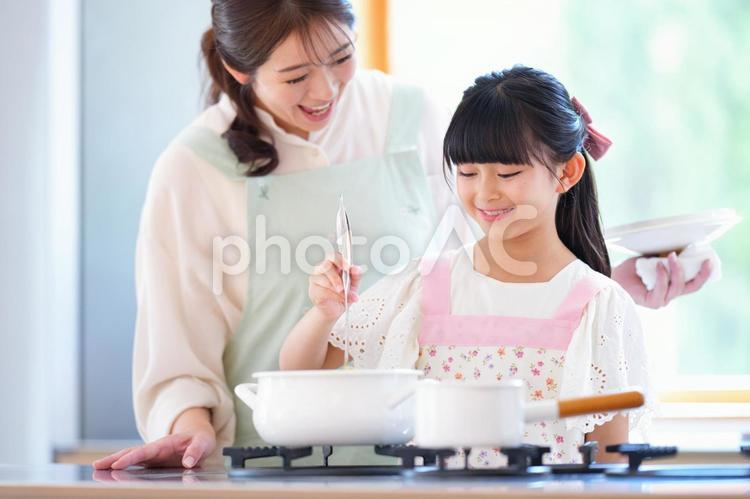 笑顔で鍋の中を見る親子 母,娘,女の子の写真素材