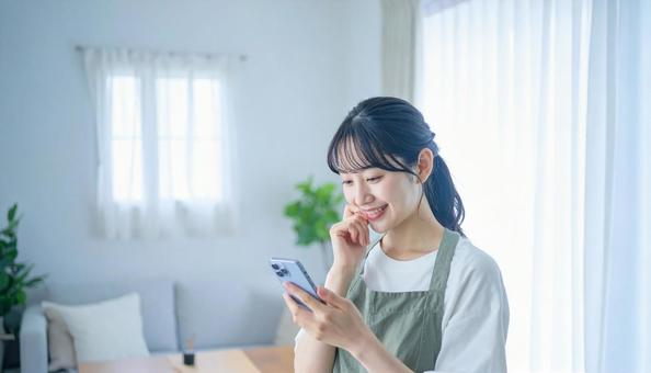 スマホでポイ活する笑顔の女性 スマホでポイ活する笑顔の女性の写真