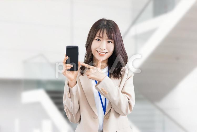スマホを指差す笑顔のビジネスウーマン 女性,ビジネス,スマホの写真素材