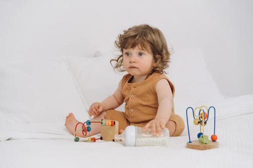哺乳瓶を触りお座りする子供 赤ちゃん,かわいい,玩具の写真素材