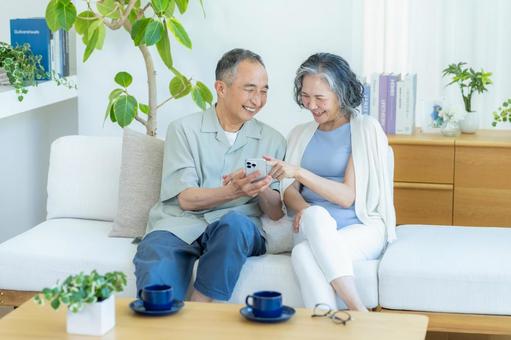 リビングでスマホを見るシニア夫婦 リビングでスマホを見るシニア夫婦 スマホ,シニア,笑顔の写真素材