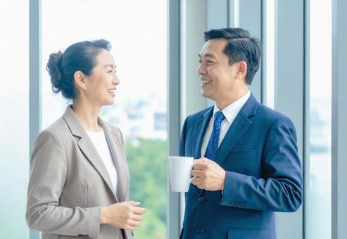 笑顔で会話する2人のビジネスパーソン 笑顔で会話する2人のビジネスパーソンの写真
