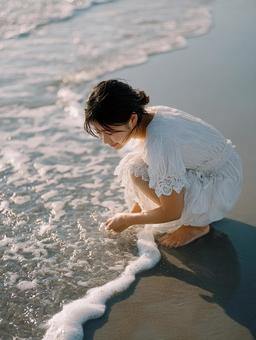 夏のビーチで波と戯れる若い日本人女性 夏のビーチで波と戯れる若い日本人女性の写真