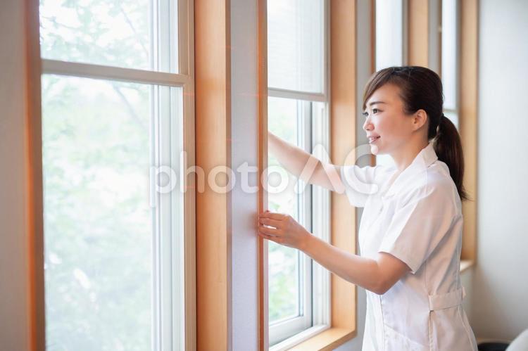 窓を開けて換気をする白衣の女性 換気,窓,外気の写真素材