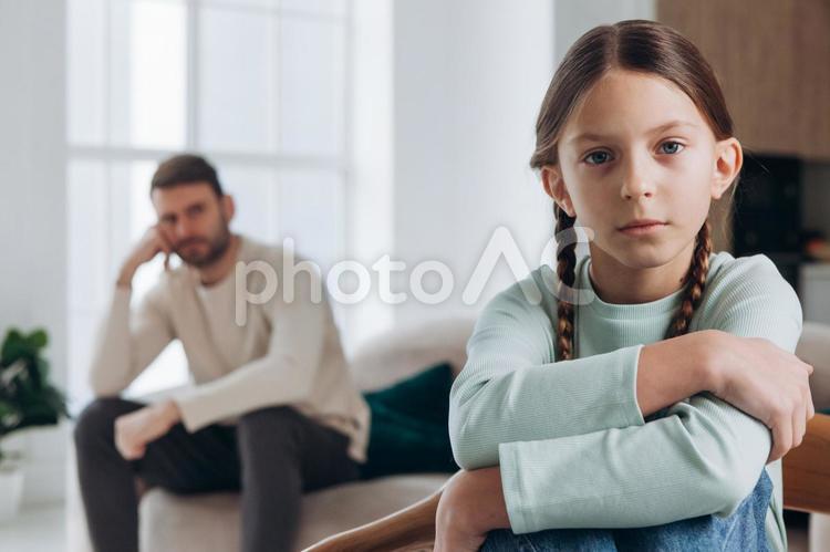 カメラ目線のおさげの女の子と不機嫌の男性 親子,女の子,カメラ目線の写真素材
