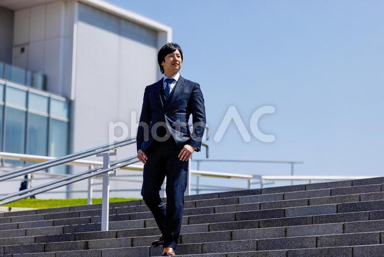 ビルの前を歩くスーツの男性 ビジネスマン,ビジネス,男性の写真素材