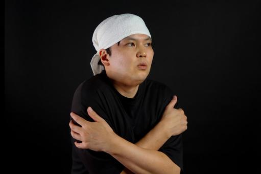 寒そうに肩を抱える男性 寒そうに肩を抱える男性の写真