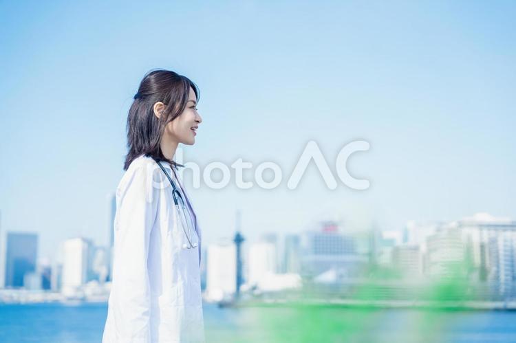 笑顔で外を歩く女性のドクター 空,看護師,資格の写真素材