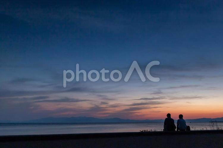 黄昏の空と肩を並べる二人の後ろ姿 二人,シルエット,カップルの写真素材