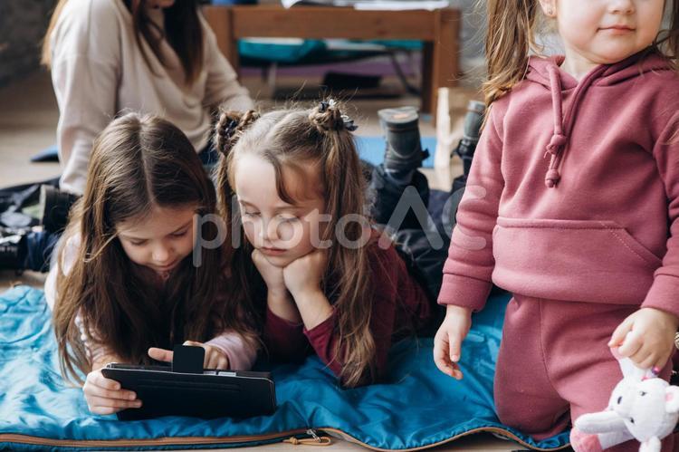 タブレットを見たりする女の子と後ろに座る女性 女の子,人物,貧困の写真素材