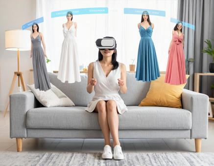 VRゴーグルを使ってドレスを選ぶ女性 VRゴーグルを使ってドレスを選ぶ女性の写真