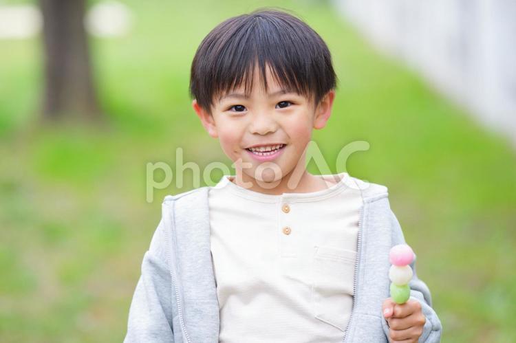 屋外で三色団子を持っている男の子 男の子,小学生,子どもの写真素材