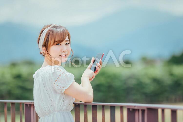 自然の中でスマホを持つ女性 スマホ,買い物,ネットショッピングの写真素材