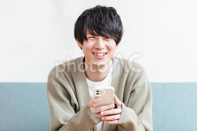 笑顔でスマホを操作する男性　 男性,スマホ,携帯電話の写真素材