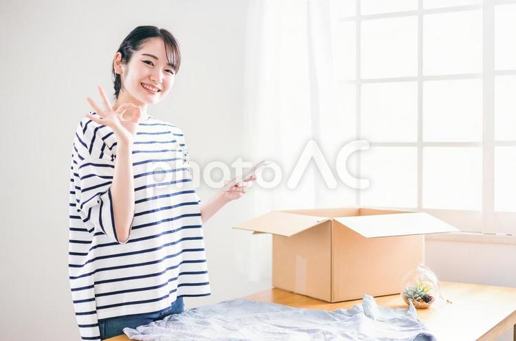 洋服をフリマアプリに出品する女性 フリマ,出品,スマホの写真素材