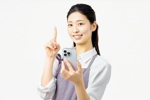 スマートフォンを持ち説明する主婦 スマートフォンを持ち説明する主婦 主婦,スマホ,スマートフォンの写真素材