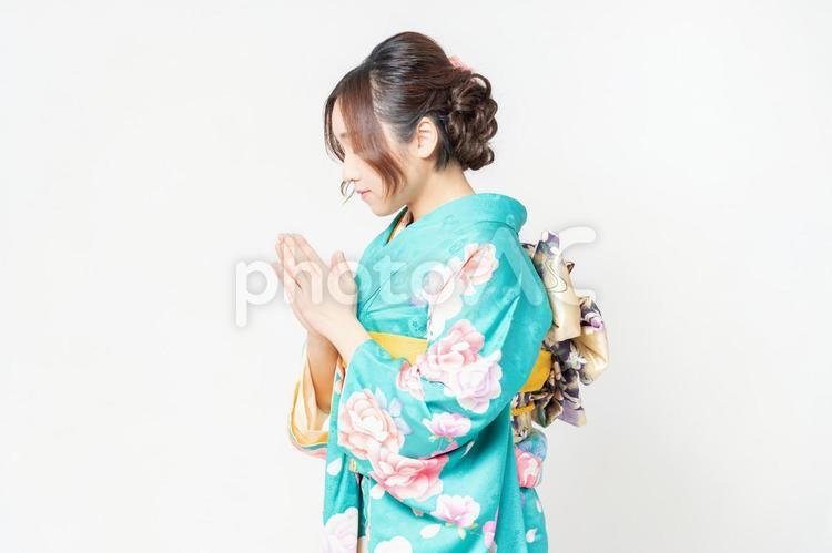 白背景の前に立って、お願いのジェスチャーをする振袖を着た女性 女性,お願い,謝るの写真素材