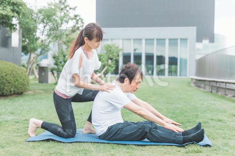 屋上でヨガをする中高年の男女 準備運動,ストレッチ,柔軟運動の写真素材