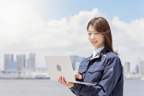 ノートパソコンを使う作業服を着た女性 女性,作業服,人物の写真素材