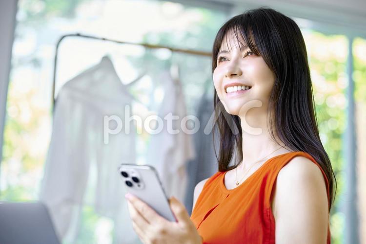 スマホを持つ　外を見る女性　リビング スマホ,女性,外を見るの写真素材