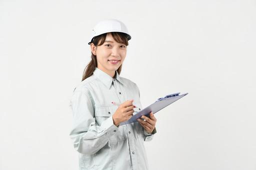 ボードを持つ作業服姿の若いアジア人女性 ボードを持つ作業服姿の若いアジア人女性 現場作業,作業着,安全管理の写真素材