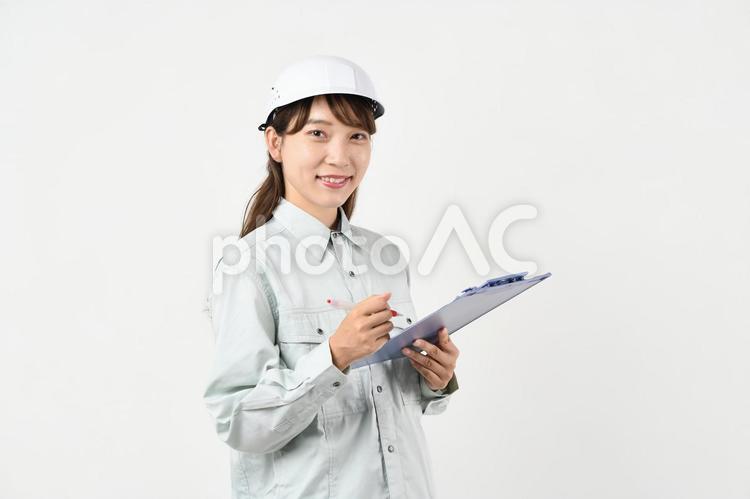 ボードを持つ作業服姿の若いアジア人女性 現場作業,作業着,安全管理の写真素材