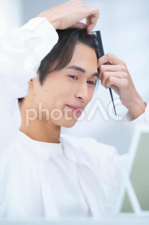 微笑みながら髪をとく男性 男性,美容男子,化粧男子の写真素材