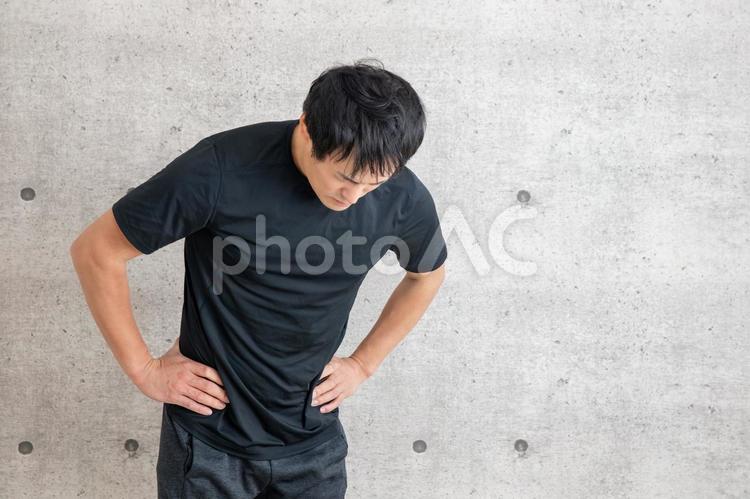 スポーツウェアを着た男性 腹痛,腰痛,息切れの写真素材
