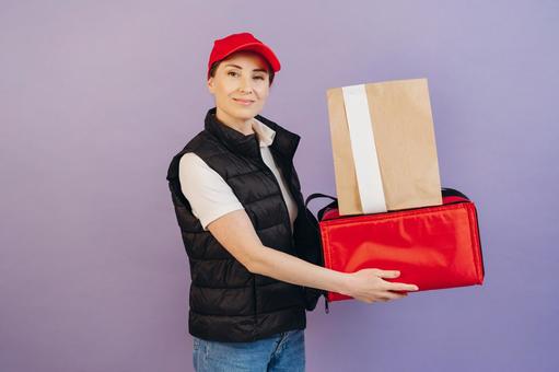 保温ピザバッグと紙袋を重ねて持つ女性配達員 配達,フードデリバリー,デリバリーの写真素材