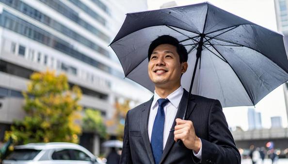 梅雨時、傘をさして街中を歩くビジネスマン 梅雨時、傘をさして街中を歩くビジネスマンの写真