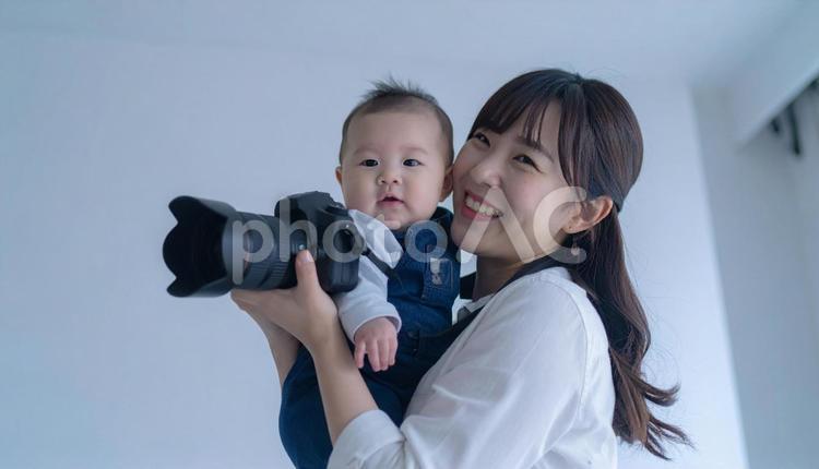 赤ちゃんに笑いかける笑顔の女性カメラマン ベビーフォトグラファー,ビジネスウーマン,ビジネスパーソンの写真素材