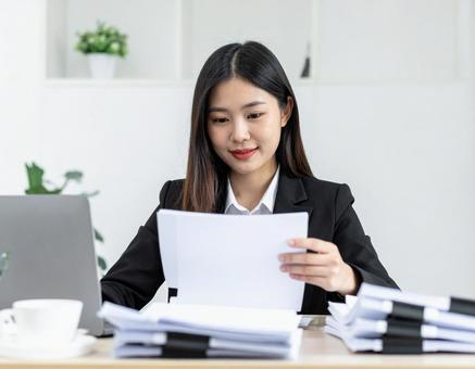 たくさんの書類を処理する女性社員 たくさんの書類を処理する女性社員の写真