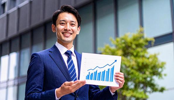 右上がりのグラフを手に持つビジネスマン 右上がりのグラフを手に持つビジネスマンの写真
