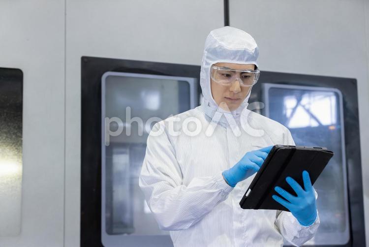 工場でタブレットを使う防護服を着た作業員 工場,タブレット,マシニングの写真素材
