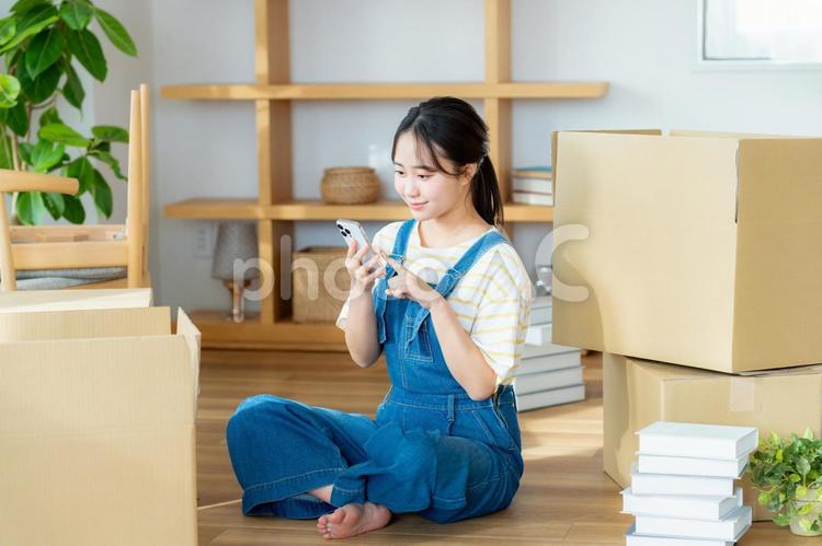引越しの準備をする若い女性 スマホ,笑顔,女性の写真素材