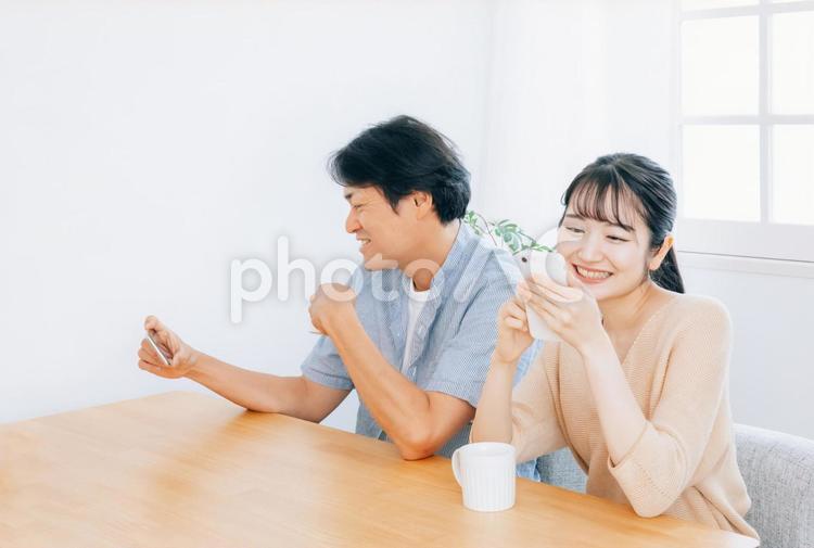 お互いにスマホを見る夫婦（笑顔） スマホ,居心地,夫婦の写真素材