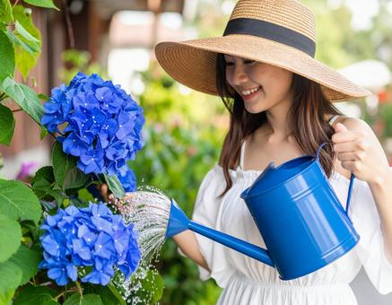 夏の朝・花に水やりする彼女の写真