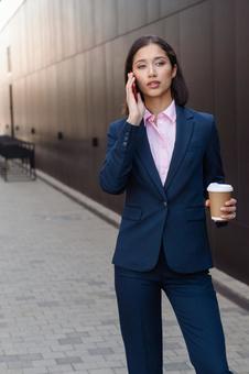 街なかでコーヒー片手に電話しているビジネスウーマン ビジネスウーマン,ビジネス,女性の写真素材